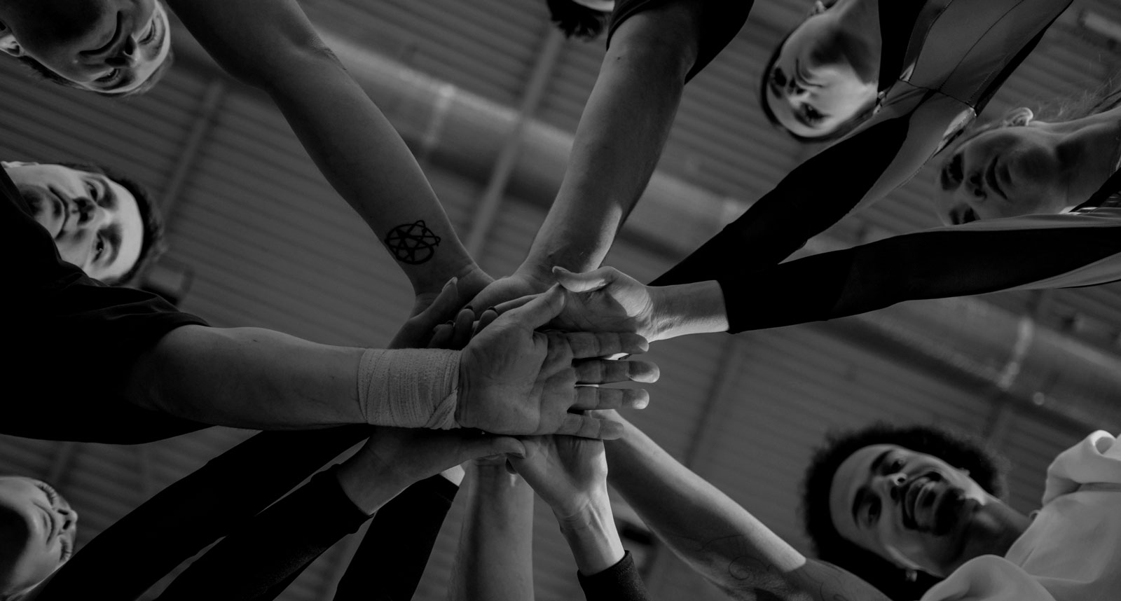 Athletes placing their hands in together, supporting one another with coaching, mentorship and financial support